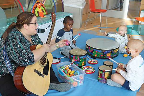 Rosemary Obi playing guitar for young children