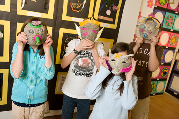 a group of children wearing artistic masks