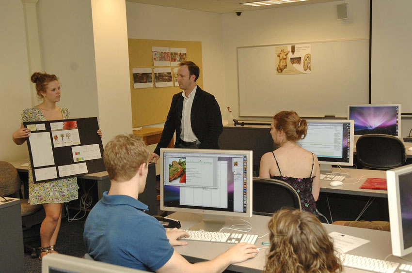 a congregation of students conduction a design critique in a computer lab