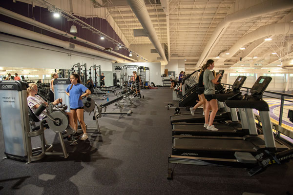 students using weight machines and treadmills, overlooking an indoor track