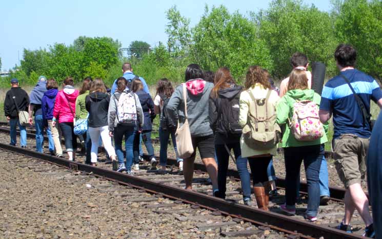 The March participants walk along railroad tracks.